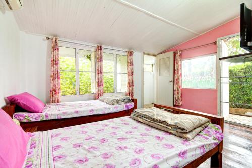 two beds in a room with pink walls and windows at Rosemary House in Pak Chong