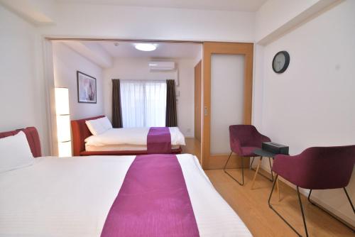 una camera d'albergo con un grande letto e due sedie di European House Reisen a Fukuoka