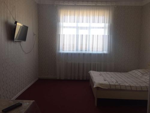 a small bedroom with a bed and a window at Керуен сарайы, гостиница in Aralʼsk