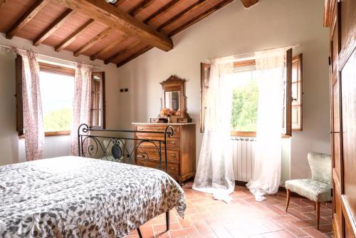 una camera con letto, cassettiera e finestre di La Villa di Primo a Cavriglia