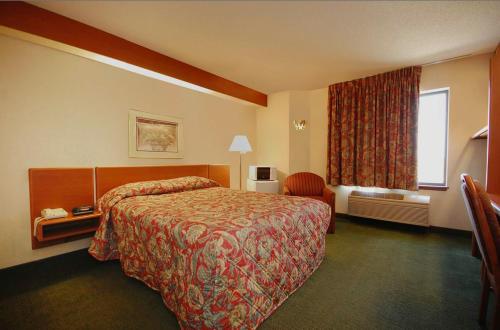 a hotel room with a bed and a window at Syracuse Inn and Suites in Syracuse