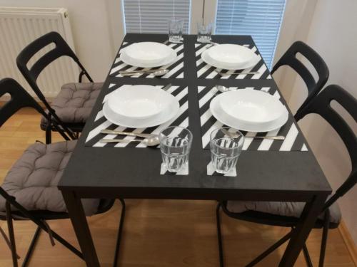 a black table with four chairs and plates and glasses at Apartment Teodora in Belgrade