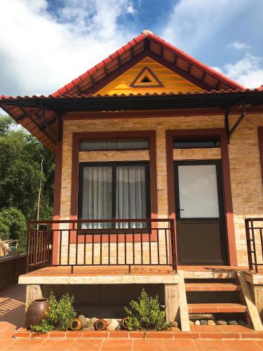 a small house with a balcony and a door at Mai Chau Xanh Bungalow in Mai Chau