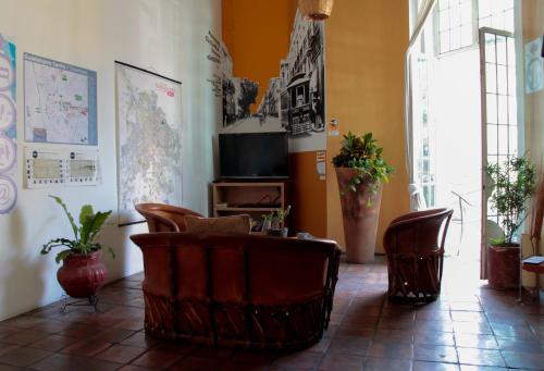 a room with chairs and a tv and a table at Hostel Hospedarte Centro in Guadalajara