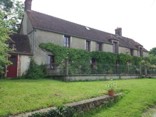 an ivy covered house with a fence and a yard at La Berlandière in Le Merlerault