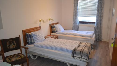 twee bedden in een kamer met een stoel en een raam bij Soniat House in Kestrup