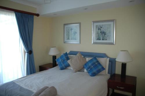 a bedroom with a bed with blue and white pillows at Ramsgate Palms H in Ramsgate