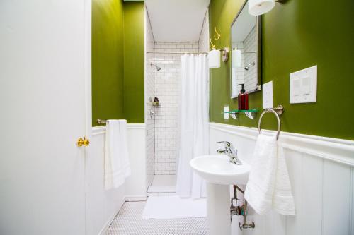 een groene badkamer met een wastafel en een spiegel bij The High Tide #3 Condo in Queens