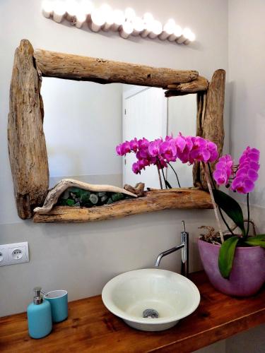 a bathroom sink with a mirror and flowers on a counter at cansantidesmonestir in La Mola