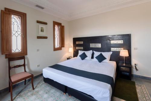 a bedroom with a large bed and a chair at Hôtel Riad Airport Marrakech in Marrakech