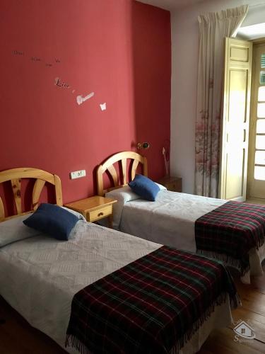 two beds in a room with red walls at Casa Tere in Sigüenza