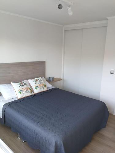 a bedroom with a large bed with a blue blanket at Papudo para 6 personas - PLAYA Y BOSQUE a metros in Papudo