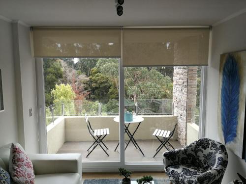 una sala de estar con una gran ventana de cristal con mesa y sillas. en Papudo para 6 personas - PLAYA Y BOSQUE a metros, en Papudo