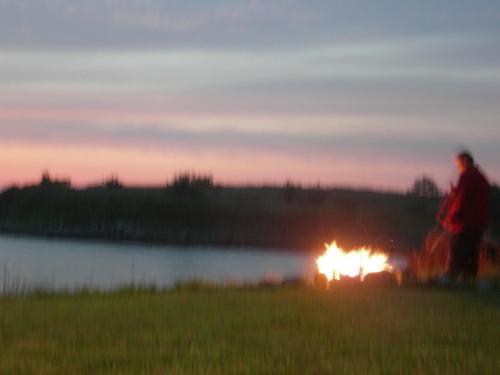 two people walking around a fire in a field at sunset at Ye Olde Argyler Lodge in Pubnico