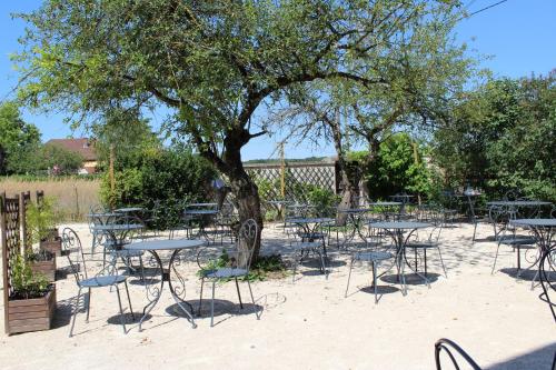 a group of tables and chairs under a tree at Le Fauverney Lodge in Fauverney