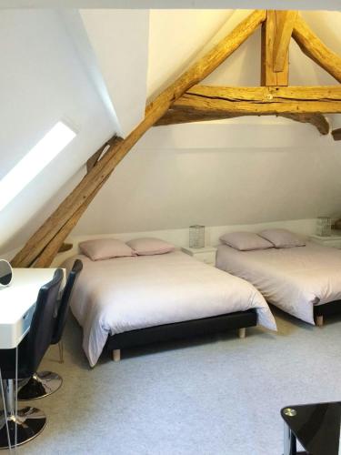 Cette chambre mansardée comprend 2 lits et une table. dans l'établissement La Pierre Précieuse, à Château-Thierry