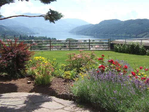 a garden with flowers and a view of a lake at Pension Paßler in Seeboden