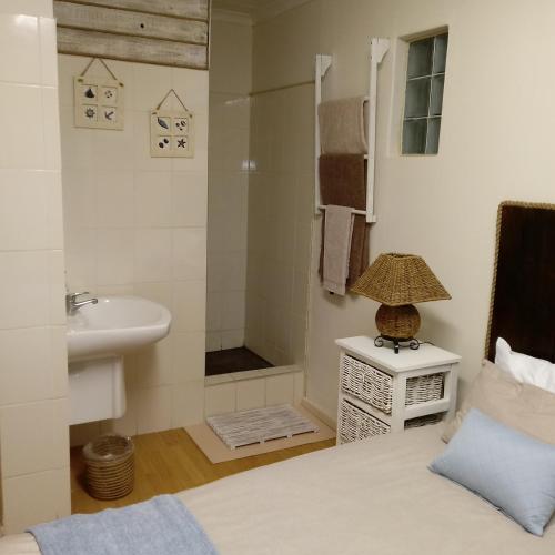a bathroom with a bed and a sink and a shower at Vincentia Odd Cottage ( self catering) in East London