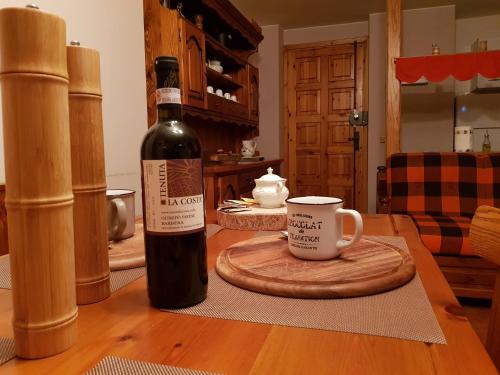 Una botella de vino y una taza sobre una mesa en Alpirosa, en Challand Saint Anselme