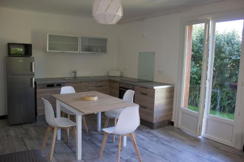 - une cuisine avec une table en bois et des chaises blanches dans l'établissement BdB nid douillet au rdc rando ressourçante, à Bagnères-de-Bigorre