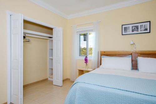 a white bedroom with a bed and a window at Sir Charles Guest House in South Palmetto Point
