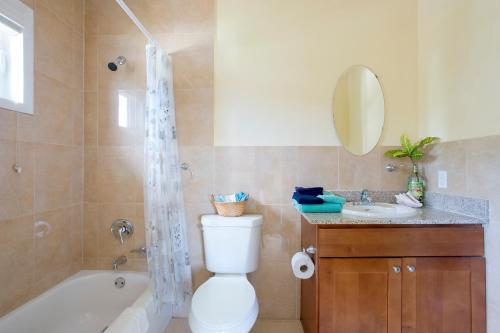 a bathroom with a tub and a toilet and a sink at Sir Charles Guest House in South Palmetto Point