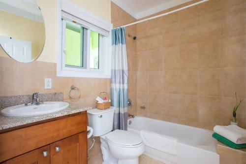 a bathroom with a sink and a toilet and a bath tub at Sir Charles Guest House in South Palmetto Point