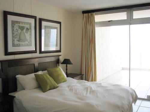 een slaapkamer met een wit bed en 2 groene kussens bij Santorini E in Margate