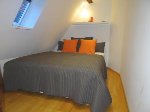 ein Bett mit orangefarbenen Kissen in einem kleinen Zimmer in der Unterkunft New Business Apartment with Flair in Hersbruck