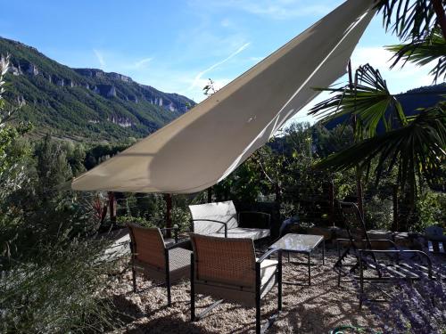 a table and chairs under a white umbrella at Le Paillier d'Etienne. in La Cresse