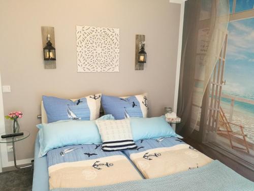 Schlafzimmer mit einem Bett mit blauer Bettwäsche und einem Fenster in der Unterkunft Ferienwohnung Südterrasse mit Kamin Bj 2019 in Timmendorfer Strand
