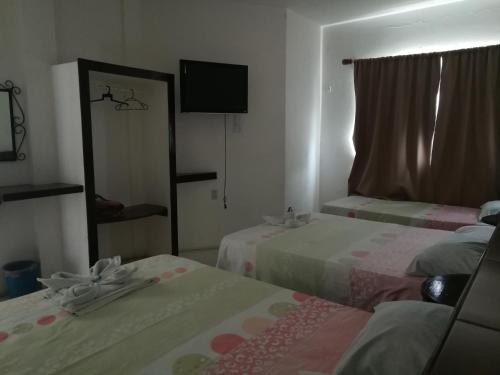 a hotel room with two beds and a mirror at Hotel Naj Kin in Palenque