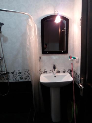 bagno con lavandino e doccia con specchio di Mari Apartment a Batumi