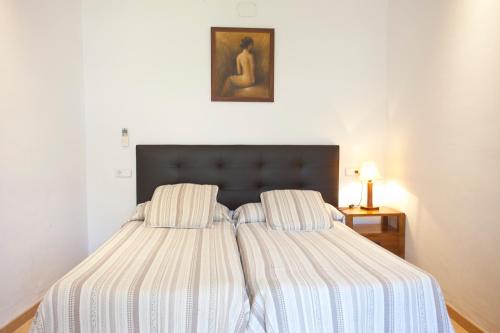 a bed with a striped comforter in a bedroom at Hotel la Vila in Sóller