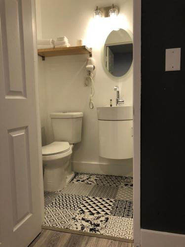 a bathroom with a toilet and a sink and a mirror at Oasis Hotel in Fort Lauderdale