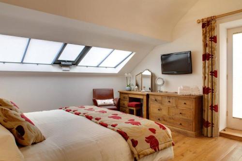 a bedroom with a bed and a desk and a tv at Squeak Cottage in Harrogate