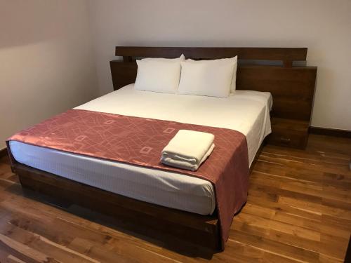 a bed with a wooden headboard and a white towel on it at Nilaveli Ocean Condos in Trincomalee