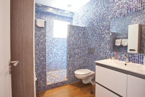 a blue tiled bathroom with a toilet and a shower at Hotel la Vila in Sóller