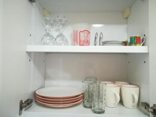a white shelf with plates and glasses on it at Monoambiente en Mendoza in Mendoza