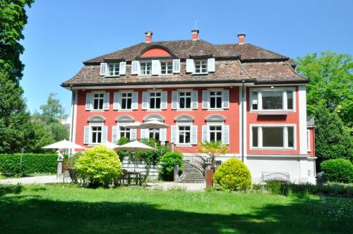 a large red and white house with a yard at Villa Jakobsbrunnen in Winterthur