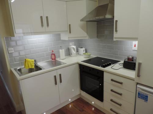 a kitchen with white cabinets and a black stove top oven at 11 Malin Street, Noreens place in Carndonagh