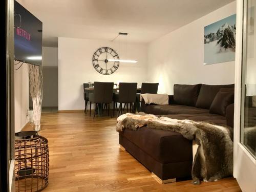 uma sala de estar com um sofá e um relógio na parede em Breathtaking Waterfall Apartment em Lauterbrunnen