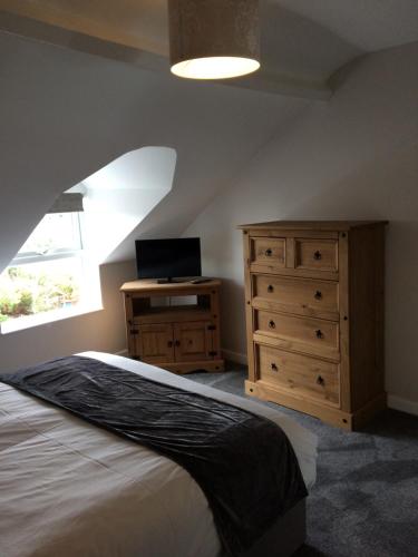 a bedroom with a bed and a dresser and a window at Swyn y Mor beach close Pet friendly hot tub in Barmouth