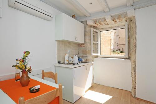cocina con armarios blancos, mesa y ventana en Studio Čikato, en Dubrovnik