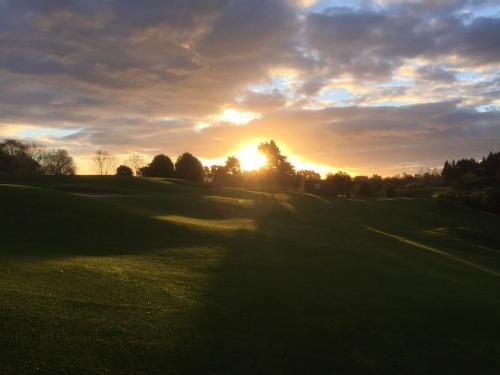 a sunset on a golf course with the sun setting at Maxwell's Golf Retreat in Bombay