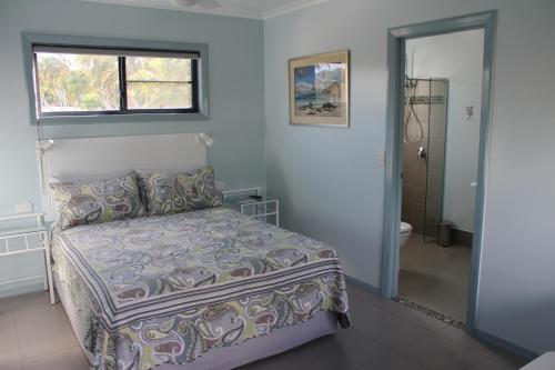 a bedroom with a bed and a window and a bathroom at Gecko Guest House in Cooktown