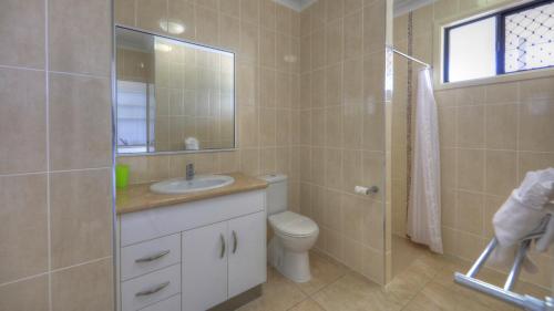 a bathroom with a sink and a toilet and a mirror at Sky View Units Bowen in Bowen