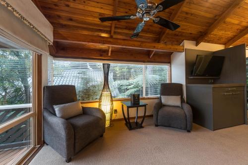 a living room with two chairs and a ceiling fan at Grand Mercure Puka Park Resort in Pauanui