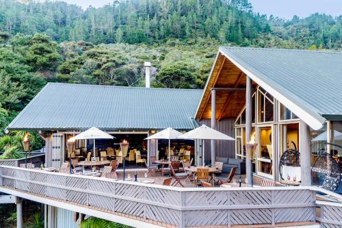 a house with a deck with tables and umbrellas at Grand Mercure Puka Park Resort in Pauanui