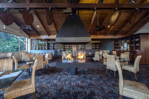 a restaurant with a fireplace in the middle of a room at Grand Mercure Puka Park Resort in Pauanui